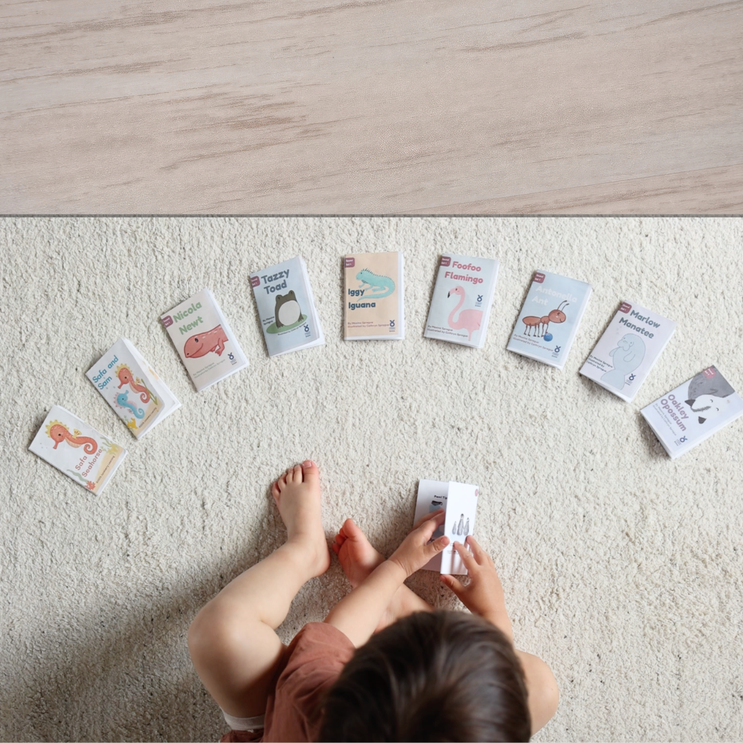Child playing with mini beginner books on a carpeted floor