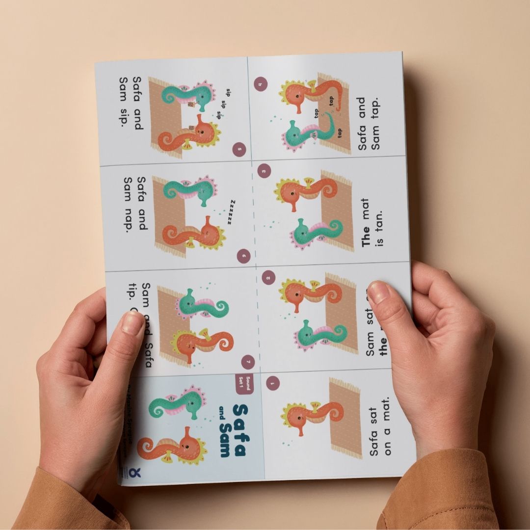 Hands holding a printed page with colorful illustrations and text on a beige background