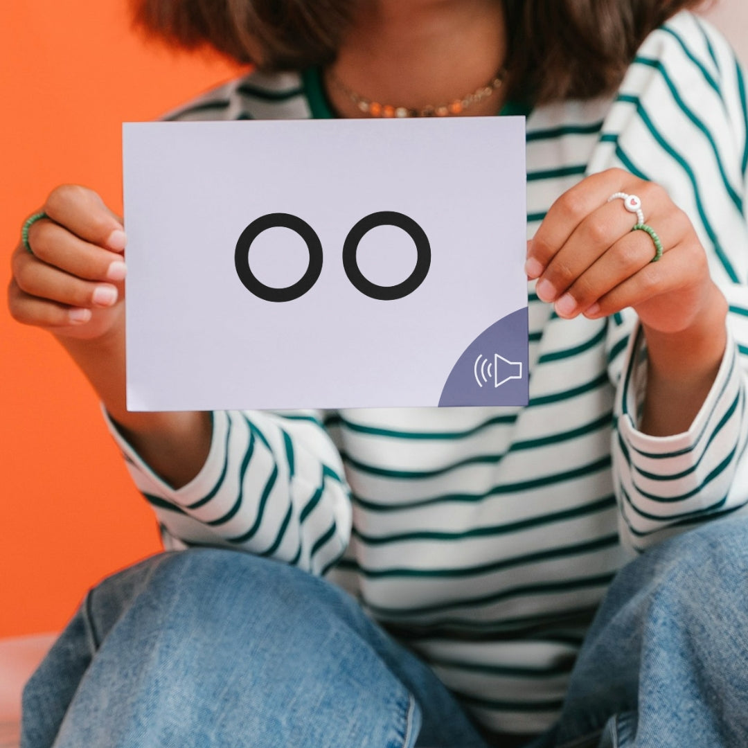 Person holding a card with two letter Os and a sound icon against an orange background