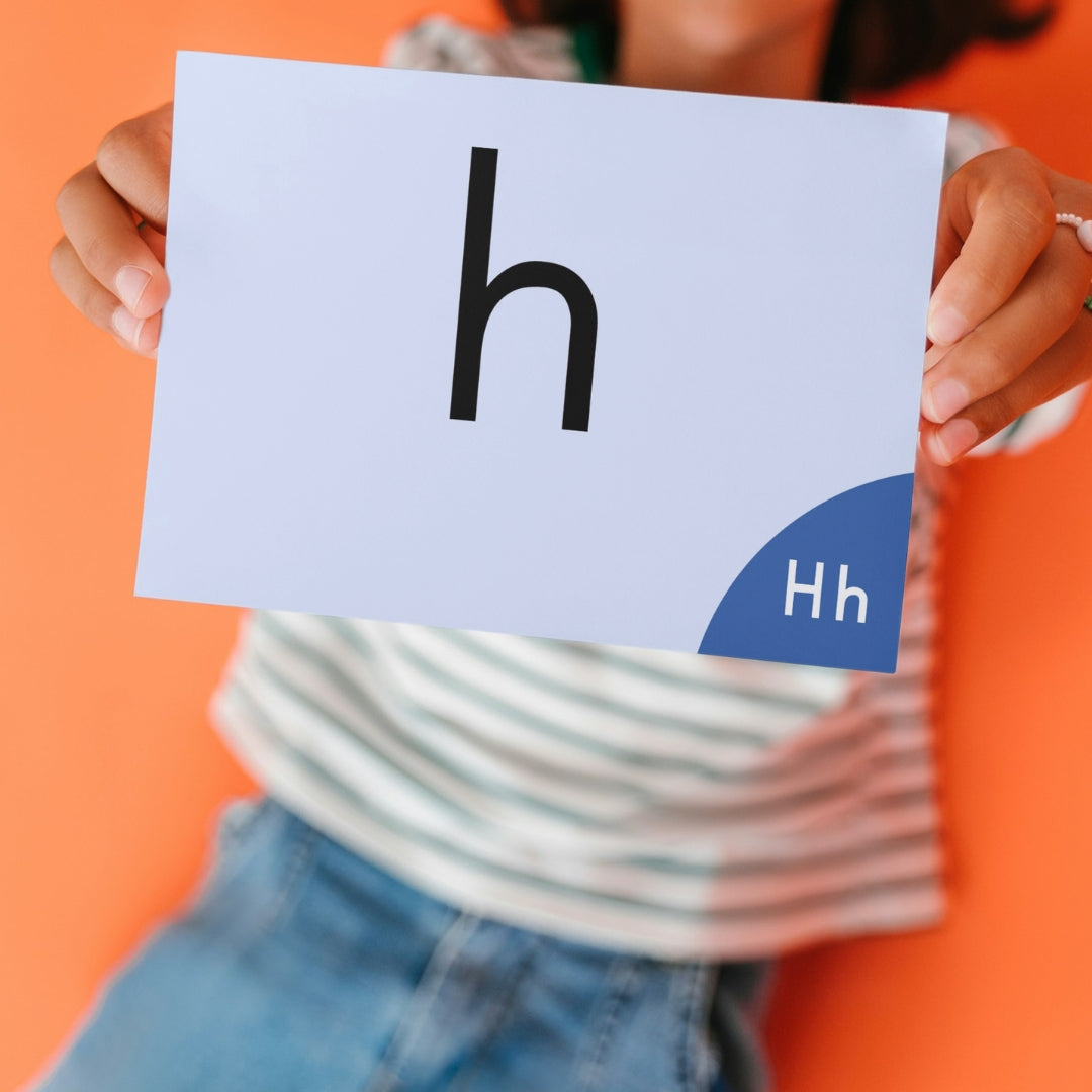 Person holding up a card with the letter 'h' against an orange background